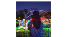 Romina seen from behind admiring the illuminated fountain and colorful lanterns during her night visit to the Philadelphia Chinese Lantern Festival in Franklin Square.