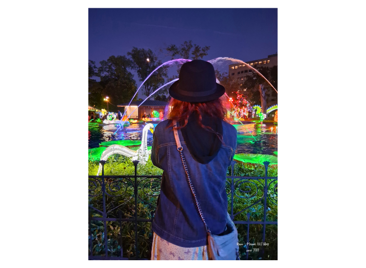 Romina de espaldas admirando la fuente iluminada y los faroles de colores durante su visita nocturna al Philadelphia Chinese Lantern Festival en Franklin Square.